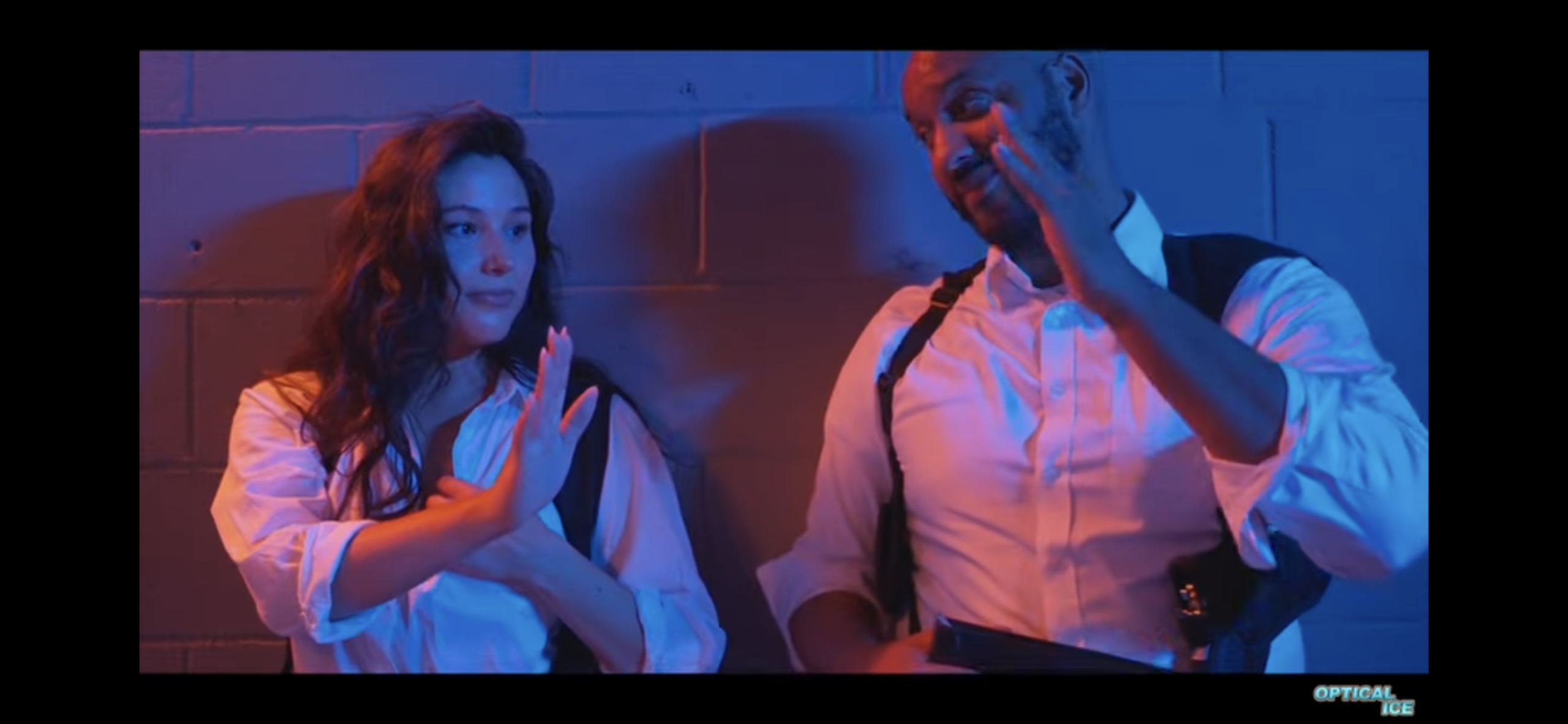 Two people gesturing with their hands under blue and red lighting.