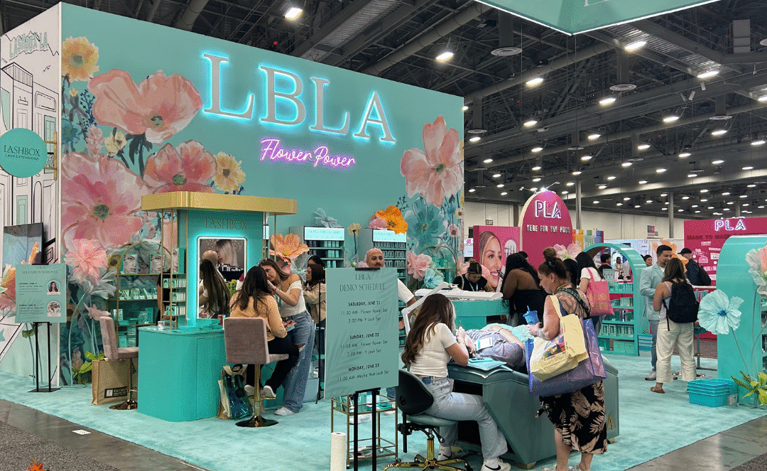 Colorful LBLA Beauty booth with floral decorations at a trade show.