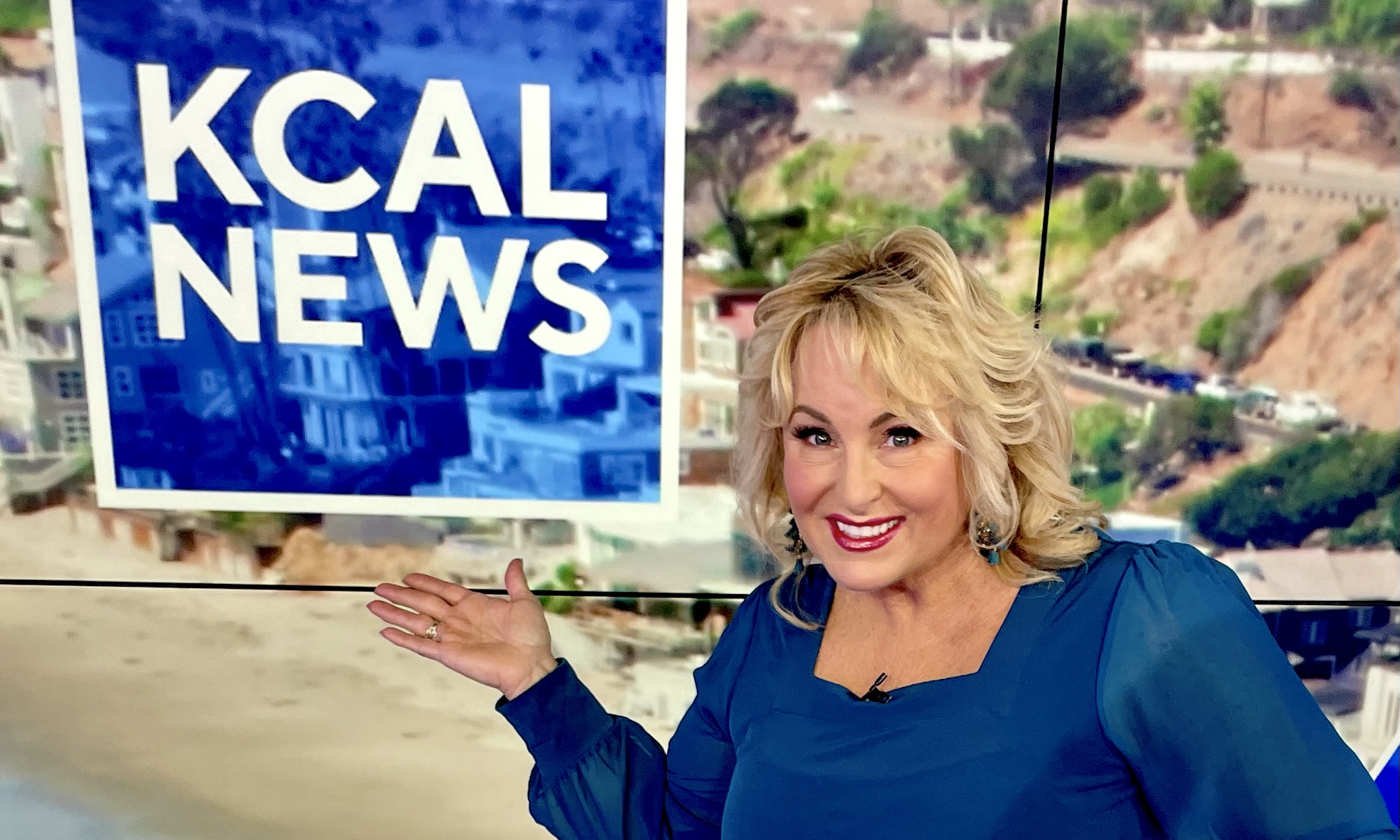 Smiling news anchor presenting in front of a CAL NEWS screen.