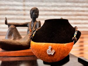 Handcrafted jewelry displayed with an artistic wooden sculpture in the background.