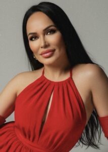 A woman with long dark hair wearing a red halter dress.