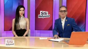 Two hosts sitting at a news desk with 'SiSi Hollywood' on screen behind them.